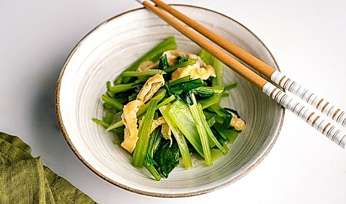 Biała japońska miska ceramiczna zawierająca Simmered Fried Tofu i Greens.