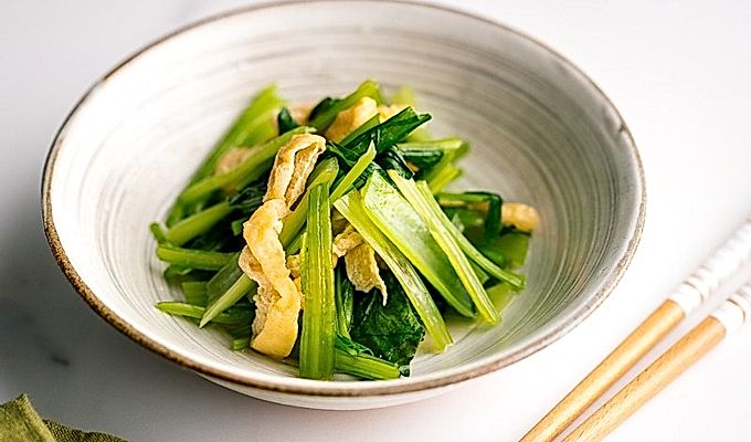 Biała japońska miska ceramiczna zawierająca Simmered Fried Tofu i Greens.