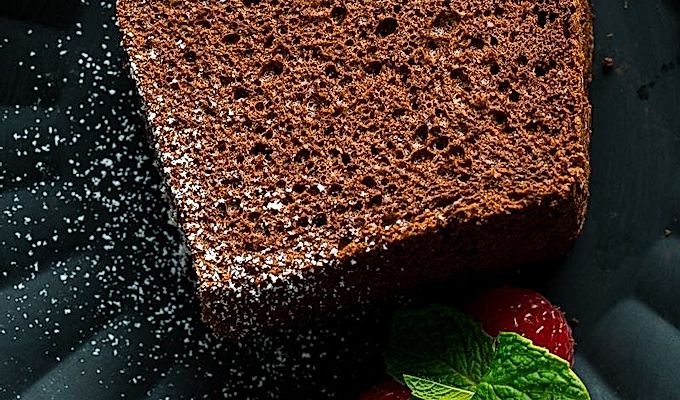 На черной матовой тарелке подают кусочек шоколадно-шифонового торта и малину.