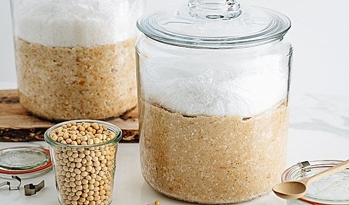 Готовится домашнее мисо; смесь сои, соли и коджи в стеклянной банке.