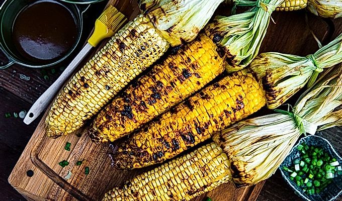 Кукуруза-гриль с масляным соусом мисо на деревянной разделочной доске.
