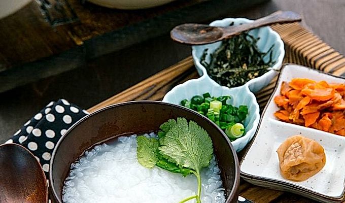 Японская рисовая каша подается в миске с лососем, зеленым луком, маринованными сливами и тертыми водорослями.