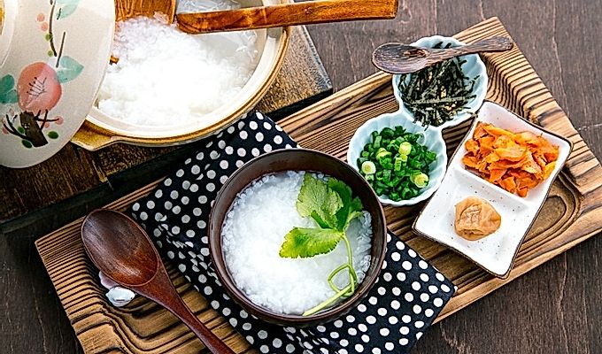Японская рисовая каша подается в миске с лососем, зеленым луком, маринованными сливами и тертыми водорослями.