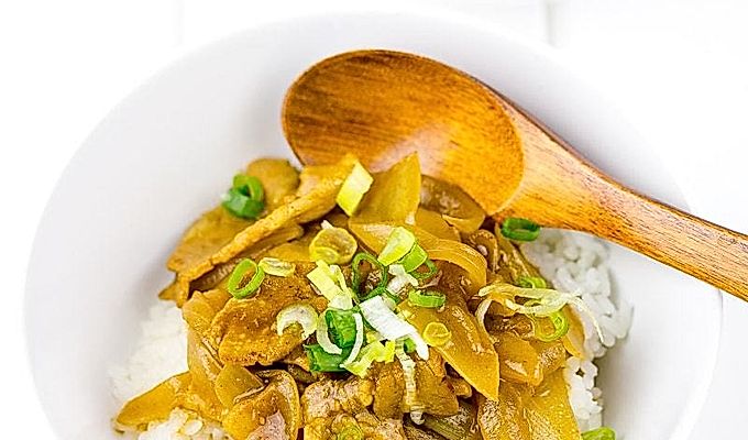 Белая миска со свиным карри и вареным рисом.