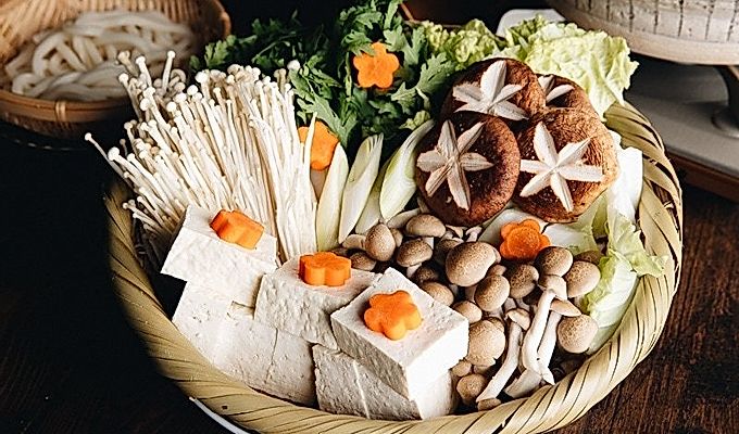 Mga sari-saring gulay, tofu, at kabute sa isang basket ng kawayan, handa nang lutuin sa Shabu Shabu.