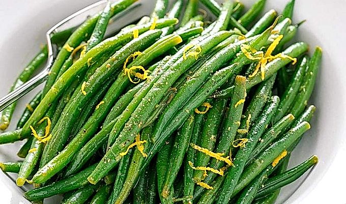 Uma tigela branca contendo feijão verde com vinagrete Yuzu.