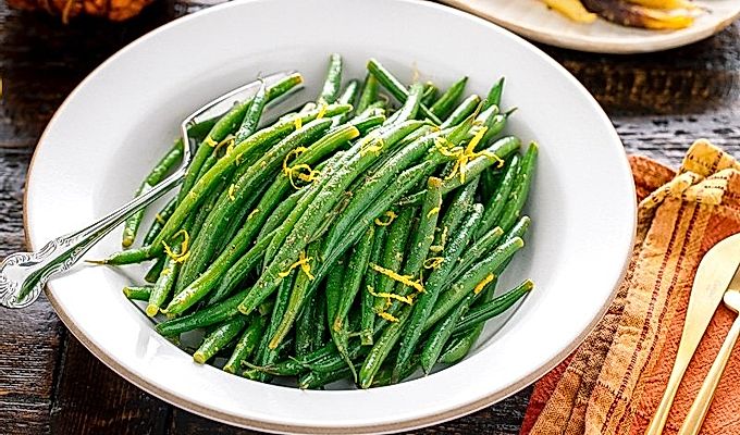 Uma tigela branca contendo feijão verde com vinagrete de Yuzu.