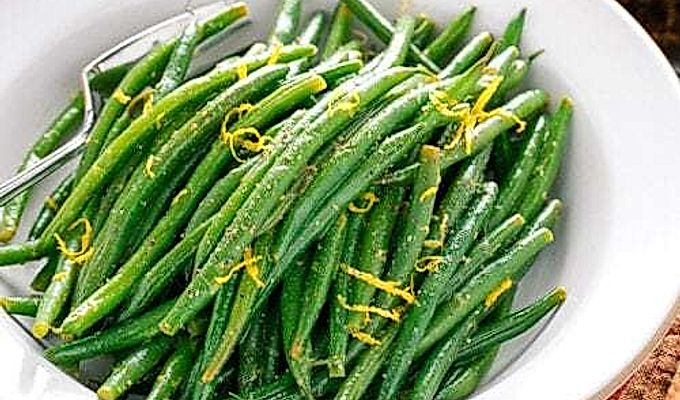 Uma tigela branca contendo feijão verde com vinagrete Yuzu.