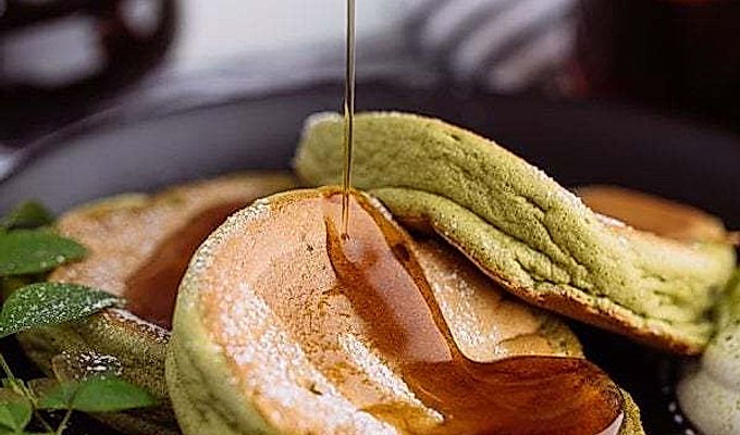 Matcha Souffle-pandekager toppet med pulversukker og frisk flødeskum.