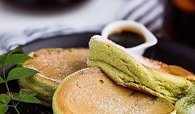 Matcha Souffle-pandekager toppet med pulversukker og frisk flødeskum.