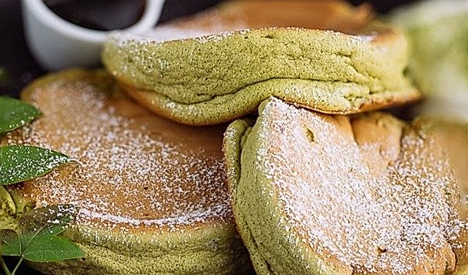 Matcha Souffle-pandekager toppet med pulversukker og frisk flødeskum.
