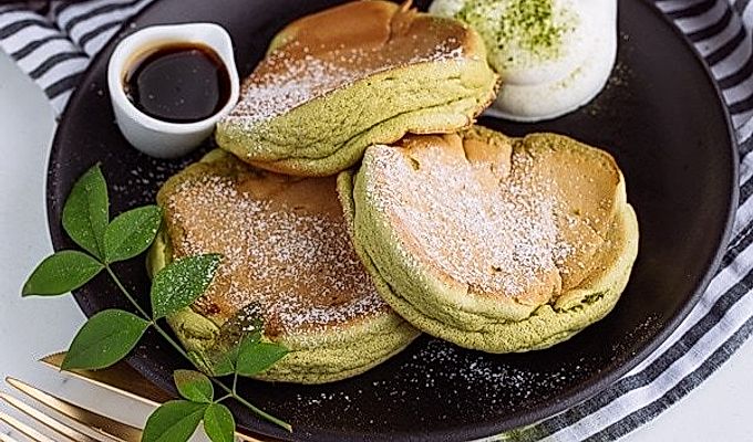 Matcha Souffle-pandekager toppet med pulversukker og frisk flødeskum.