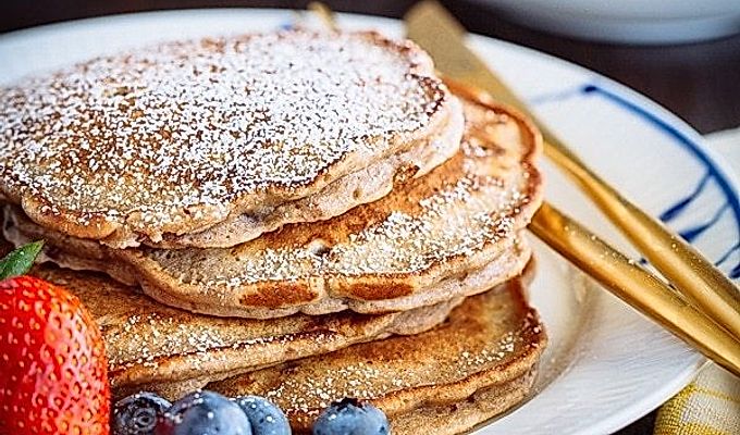 Pancake di fagioli rossi con fragole e mirtilli sul piatto bianco.