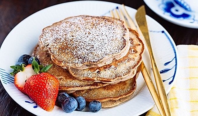 Pancake di fagioli rossi con fragole e mirtilli sul piatto bianco.