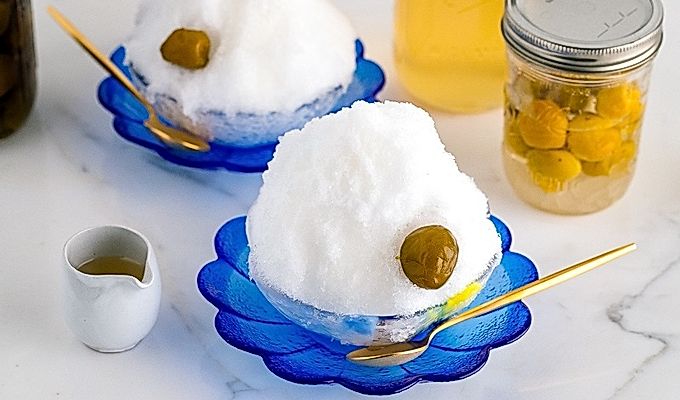 Чаша из синего стекла, содержащая ледяную стружку, сливовый сироп умэ и компот умэ.