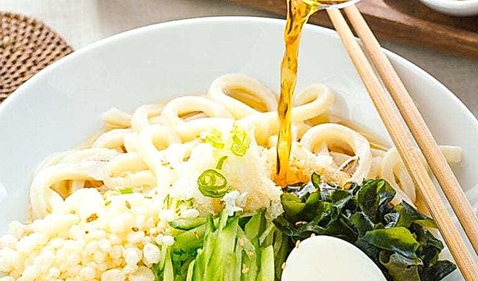 Una ciotola bianca contenente udon noodles freddi, tenk…