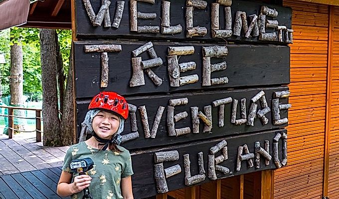 девушка перед вывеской Tree Adventure Furano