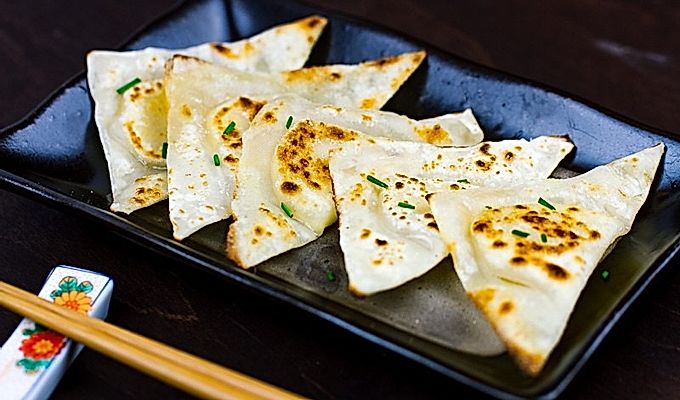 Укусы Wonton сыра на черной тарелке.