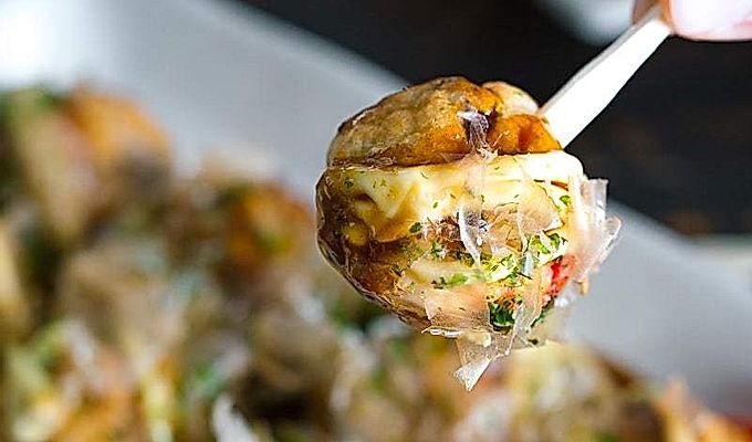 Valge plaat, mis sisaldab Takoyakit (Octopus Balls) ja mille peal on helde tilk takoyaki kastet, Jaapani majoneedot, aonorit, katsuobushit.