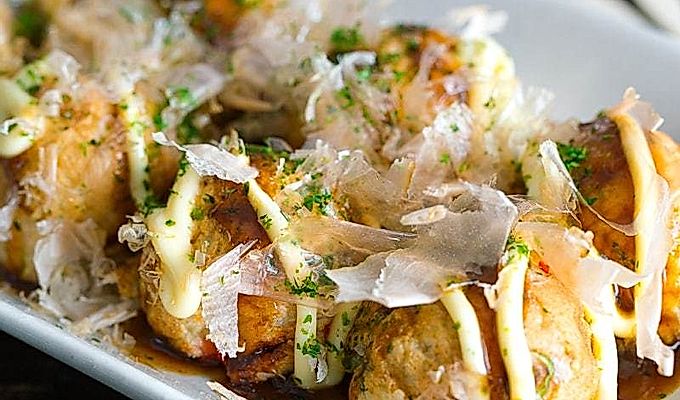 Valge plaat, mis sisaldab Takoyakit (Octopus Balls) ja mille peal on helde tilk takoyaki kastet, Jaapani majoneedot, aonorit, katsuobushit.