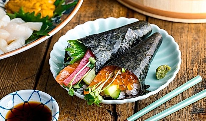 Ein hellgrüner Teller mit zwei Arten von Temaki Sushi (Hand Roll Sushi) - Lachs- und Thunfisch-Rolle und Lachs- und Ikura-Rolle.