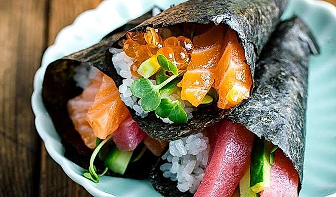 Ein hellgrüner Teller mit drei Arten von Temaki Sushi (Hand Roll Sushi) - Lachs und Thunfisch, Lachs und Ikura sowie Thunfisch und Gurke.
