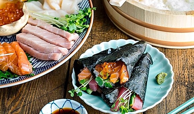 Ein hellgrüner Teller mit drei Arten von Temaki Sushi (Hand Roll Sushi) - Lachs und Thunfisch, Lachs und Ikura sowie Thunfisch und Gurke.