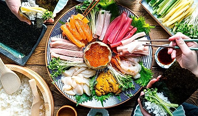 Eine Sashimi-Platte mit verschiedenen Sashimi (Thunfisch, Lachs, Amaebi, Uni, Jakobsmuschel, Kanpachi, Ikura und mehr), Sushi-Reis und Gemüseplatte.