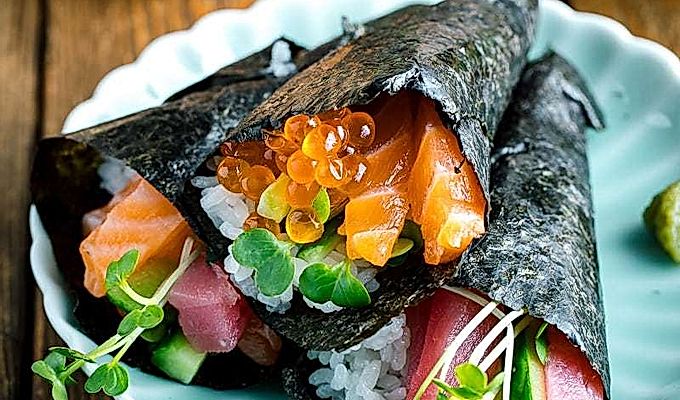 Ein hellgrüner Teller mit drei Arten von Temaki Sushi (Hand Roll Sushi) - Lachs und Thunfisch, Lachs und Ikura sowie Thunfisch und Gurke.