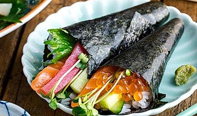 Ein hellgrüner Teller mit zwei Arten von Temaki Sushi (Hand Roll Sushi) - Lachs- und Thunfisch-Rolle und Lachs- und Ikura-Rolle.