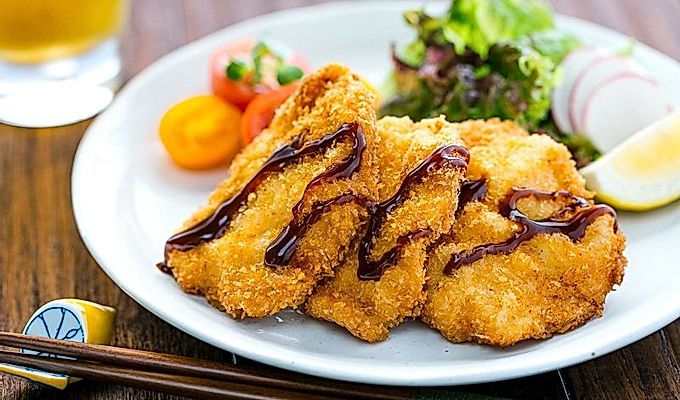 Куриный кацу подается на тарелке вместе с весенним салатом.