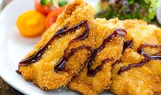 Куриный кацу подается на тарелке вместе с весенним салатом.