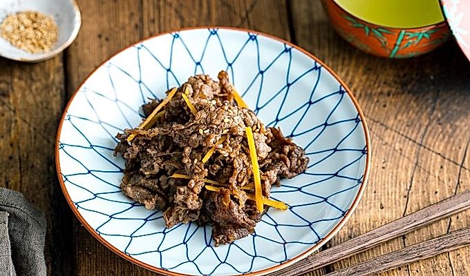 Un plat japonès blanc i blau que conté vedella sofregida amb gingebre (Shigureni).