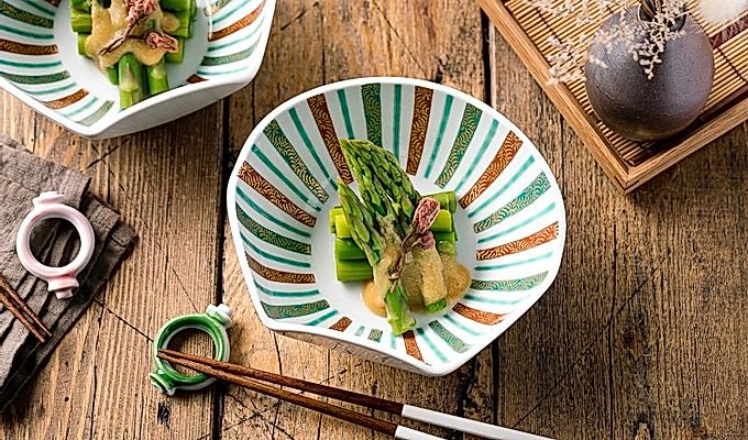 Un cuenco con forma de concha que contiene espárragos con aderezo de miso (Karashi Sumisoae) aderezado con flor de cerezo en escabeche con sal.