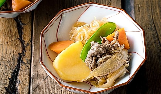 Бело-красная миска, содержащая Nikujaga (японское тушеное мясо и картофель).