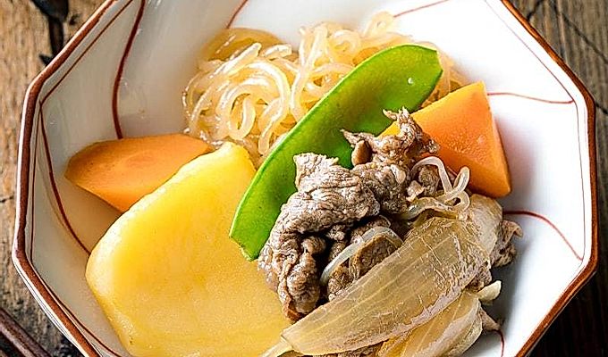 Бело-красная миска, содержащая Nikujaga (японское тушеное мясо и картофель).